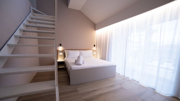 A modern hotel room with a staircase, a large bed, and a view through sheer curtains. - Be Mate Torino Centro (Turin)