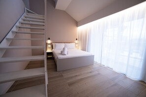 A modern hotel room with a staircase, a large bed, and a view through sheer curtains. - Be Mate Torino Centro (Turin)