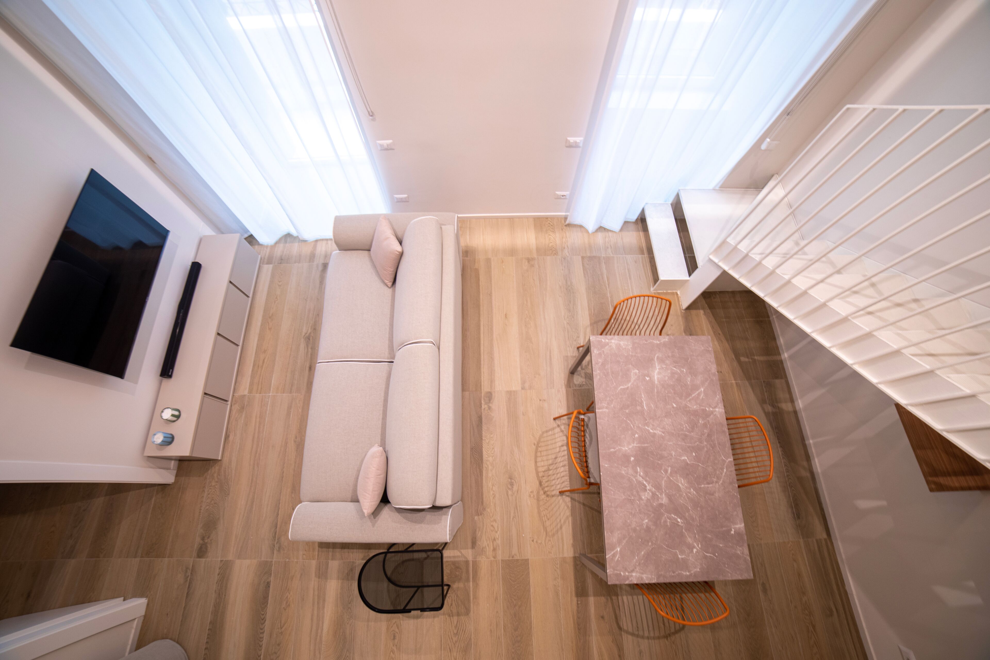 Un espacio habitable moderno y funcional con sofá, una mesita y televisor instalado en la pared.