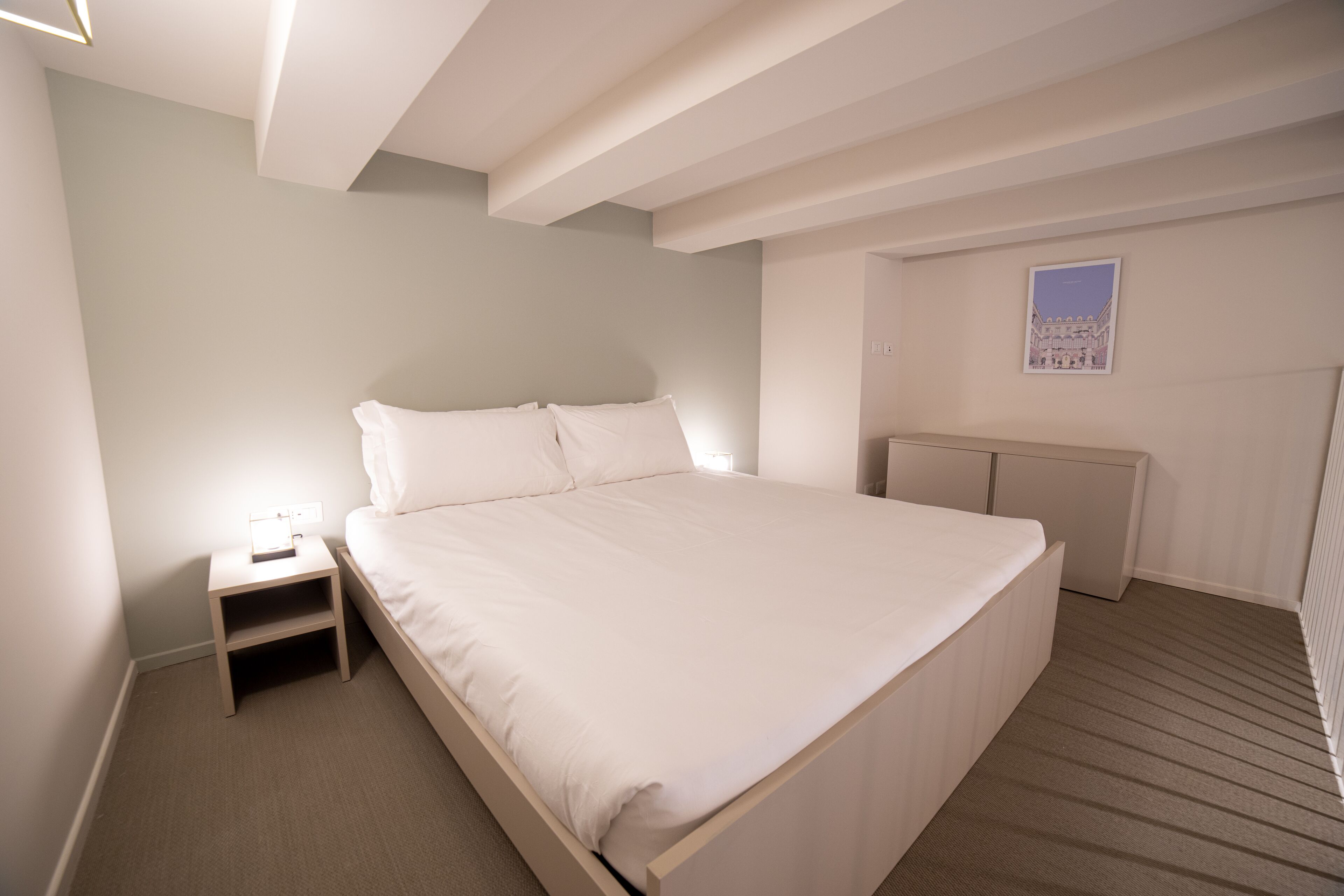 Una camera da letto con un letto, un comodino e una piccola credenza.