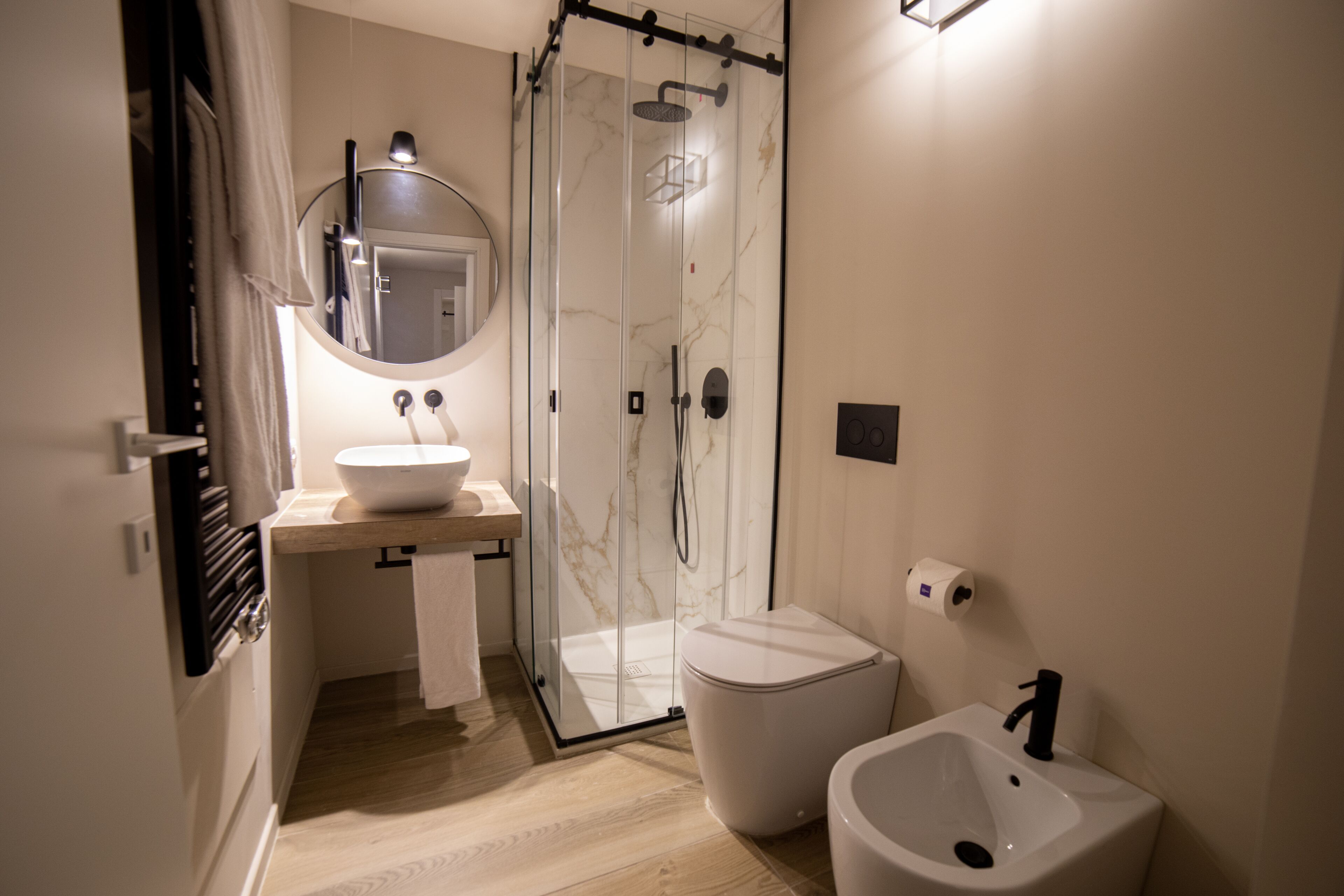 A modern bathroom with a glass-enclosed shower, a white sink, and a bidet.