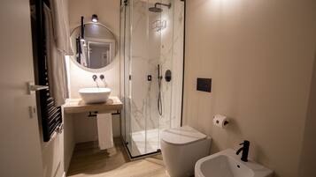 A modern bathroom with a glass-enclosed shower, a white sink, and a bidet.