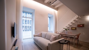 A modern living room with a sofa, a coffee table, and a dining area with chairs and a table. - Be Mate Torino Centro (Turin)