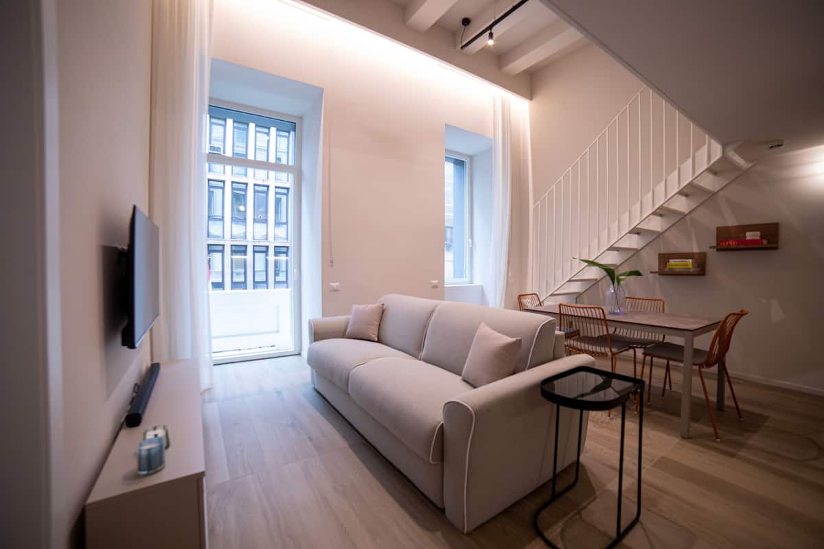A modern living room with a sofa, a coffee table, and a dining area with chairs and a table.