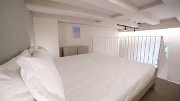A modern hotel room with a large bed, a bedside table, and a view of the city through the window.