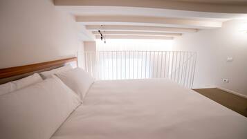 Un dormitorio con una cama grande, cabecera de madera y balcón con barandilla.