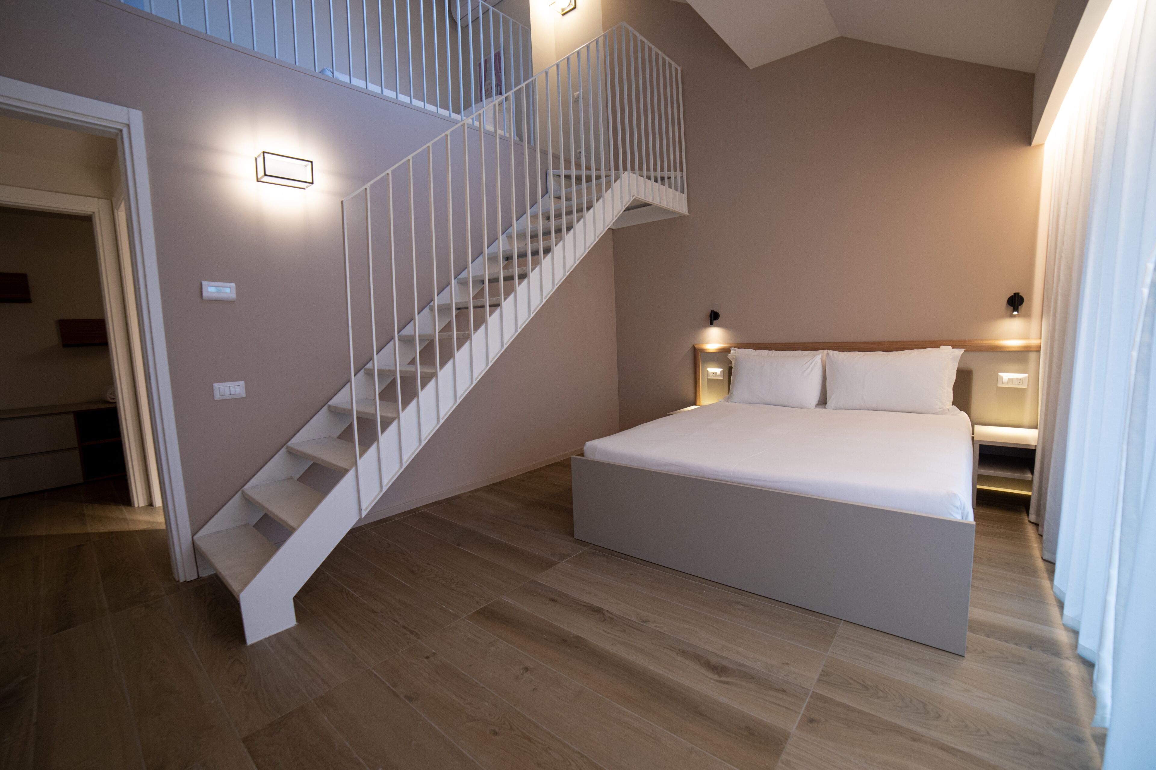 Un dormitorio con una cama grande, una escalera y una mesita de noche con lámpara.