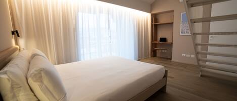 A bedroom with a bed, a desk, and a chair.