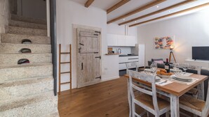 A modern kitchen with white cabinets, a wooden dining table, and a staircase with stone steps. - David House In The City Center (Olbia)