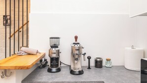A kitchen with a coffee machine, a grinder, a jar, and a roll of paper towels. - David House In The City Center (Olbia)