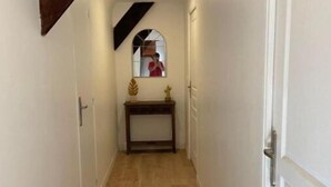 A narrow hallway with wooden flooring, white walls, and a wooden beam on the left. - Maison Périgoudine (Saint-Philippe-d'Aiguille)