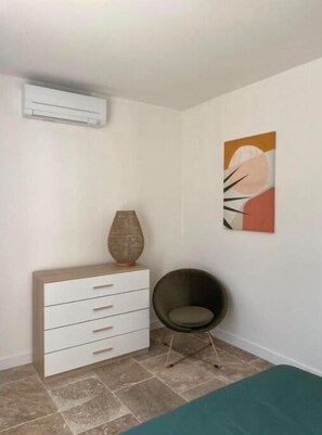 A room with a white dresser, a chair, and a painting on the wall.