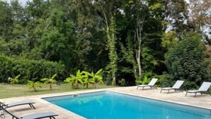 A rectangular swimming pool with a tiled deck, surrounded by lush greenery and trees. - Maison Périgoudine (Saint-Philippe-d'Aiguille)