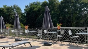 An outdoor patio area with lounge chairs and umbrellas, surrounded by a fence and trees in the background. - Maison Périgoudine (Saint-Philippe-d'Aiguille)