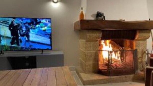 A room with a television, a stone fireplace, and a wooden table. - Maison Périgoudine (Saint-Philippe-d'Aiguille)