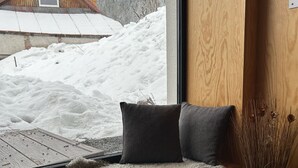 Een gezellig zitgedeelte met uitzicht op een besneeerd landschap en een houten chalet.