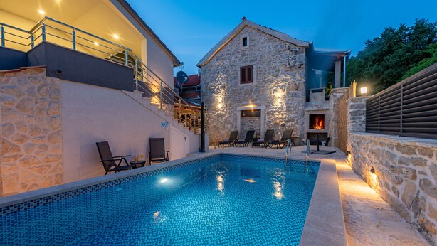 A swimming pool with stone walls and a stone building in the background. - Villa Izvor with heated pool, rural place (Bribir)