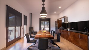 Cozinha moderna com mesa e cadeiras de madeira, uma janela grande e forno embutido.