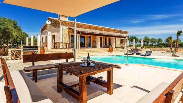 Uma villa com piscina, área de estar externa e fachada de pedra.