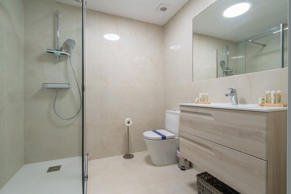 Enjoy a refreshing shower in the bathroom, featuring a glass-enclosed shower with a handheld showerhead and a handheld faucet.