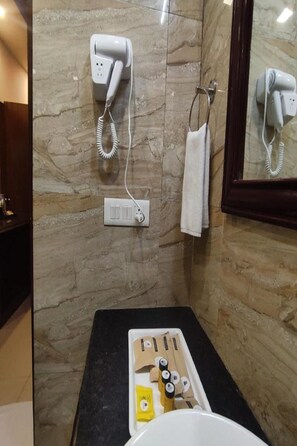 A bathroom with a marble wall, a hairdryer, a towel rack, and a tray with toiletries.