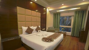 Habitación de hotel con una cama grande, cabecera de madera y vistas a zonas verdes por la ventana.