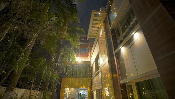 Un edificio moderno con una entrada bien iluminada, rodeado de palmeras.