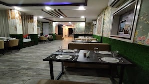 Un restaurante con una barra larga, varias mesas y cabinas. Hay sillas y mesas dispuestas para comer.