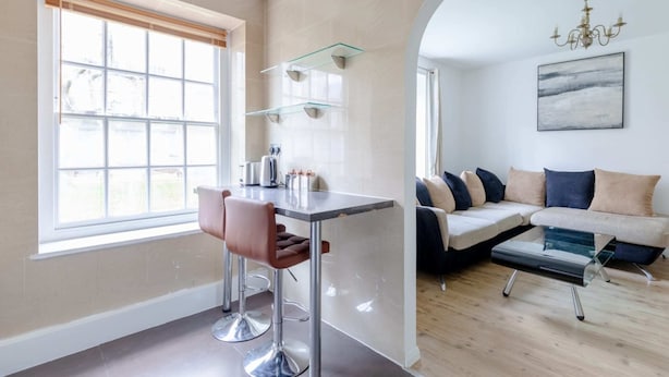 Una sala de estar moderna con un sofá, una mesa de centro de vidrio y una zona de comedor con una mesa y sillas.