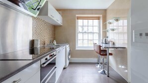Una cocina moderna con electrodomésticos de acero inoxidable, salpicadero de azulejos y un ventanal que proporciona luz natural.