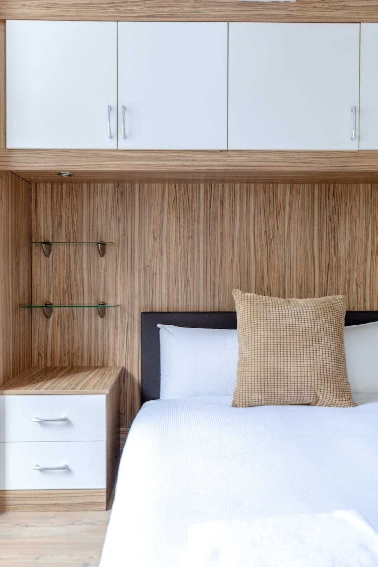 Een slaapkamer met een bed, nachtkastje en een kledingkast.