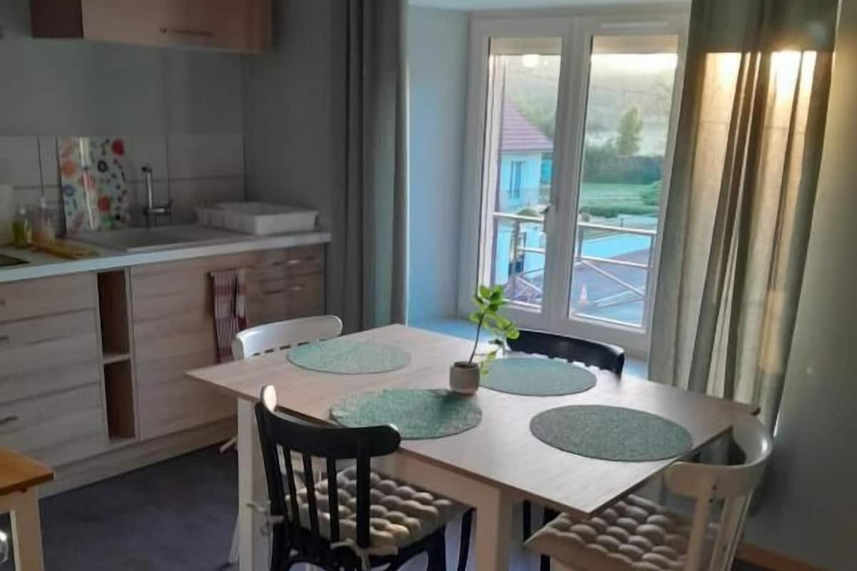 Ein Essbereich mit Tisch und Stühlen, einem Fenster mit Vorhängen und Blick ins Freie.
