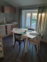 Un comedor con mesa y sillas, una ventana con cortinas y vistas al exterior.