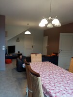 Un comedor con una mesa cubierta con mantel floreado, una silla de mimbre y una lámpara colgante.