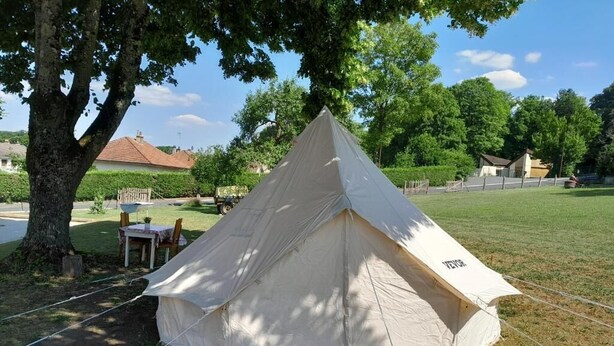 A large, beige tent set up in a grassy area with trees and a house in the background. - Gîte du capitaine (Maranville)