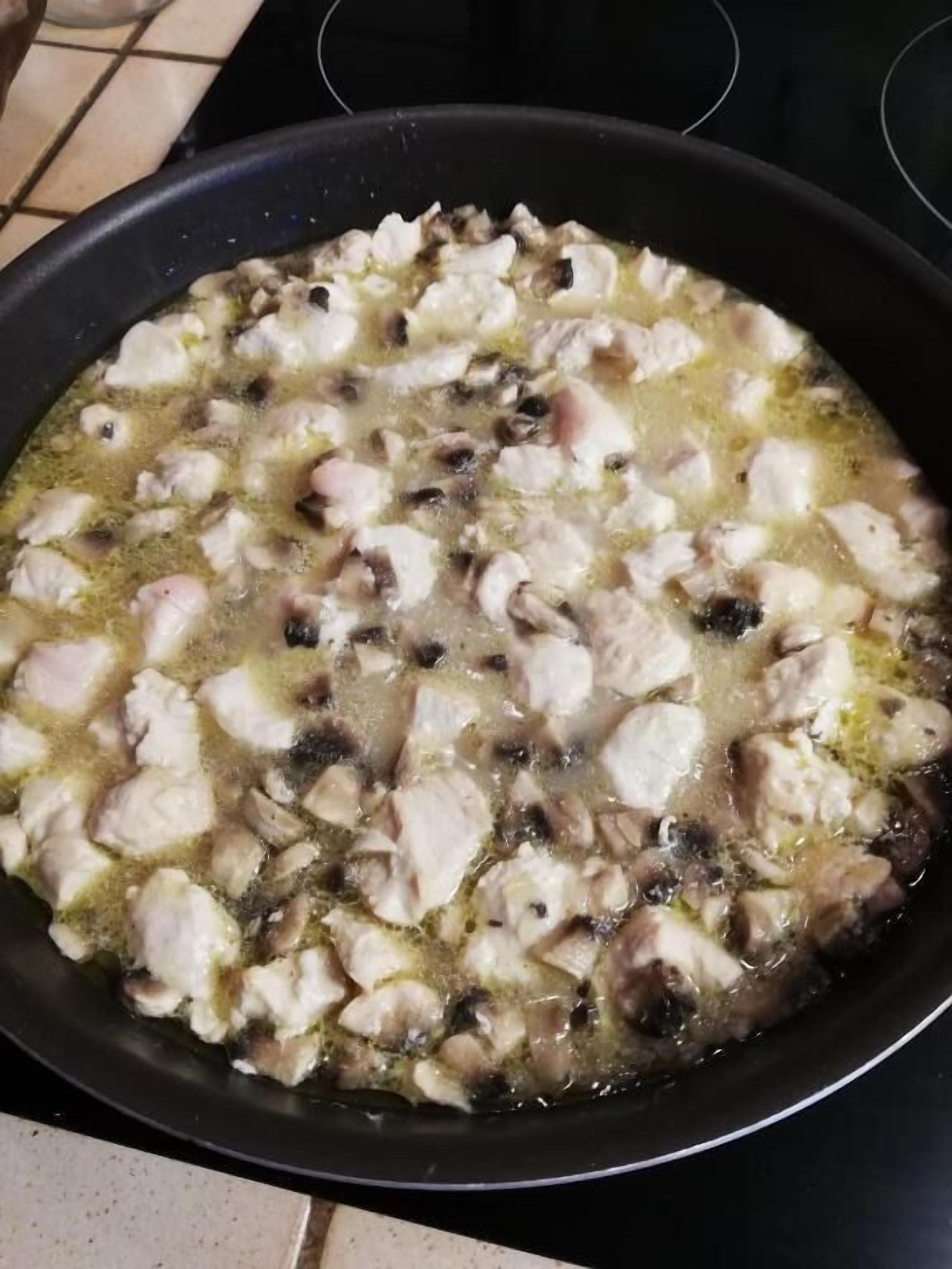 A pan with chicken and mushrooms being cooked.