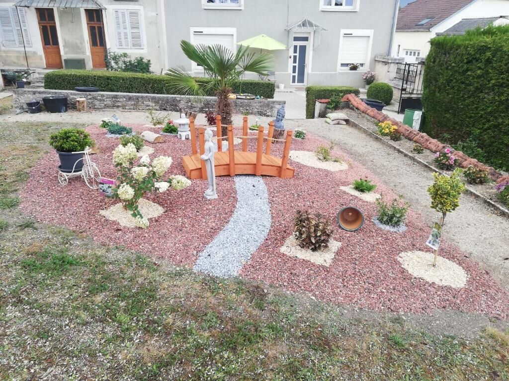 A garden with a circular wooden bench, a palm tree, and various plants.