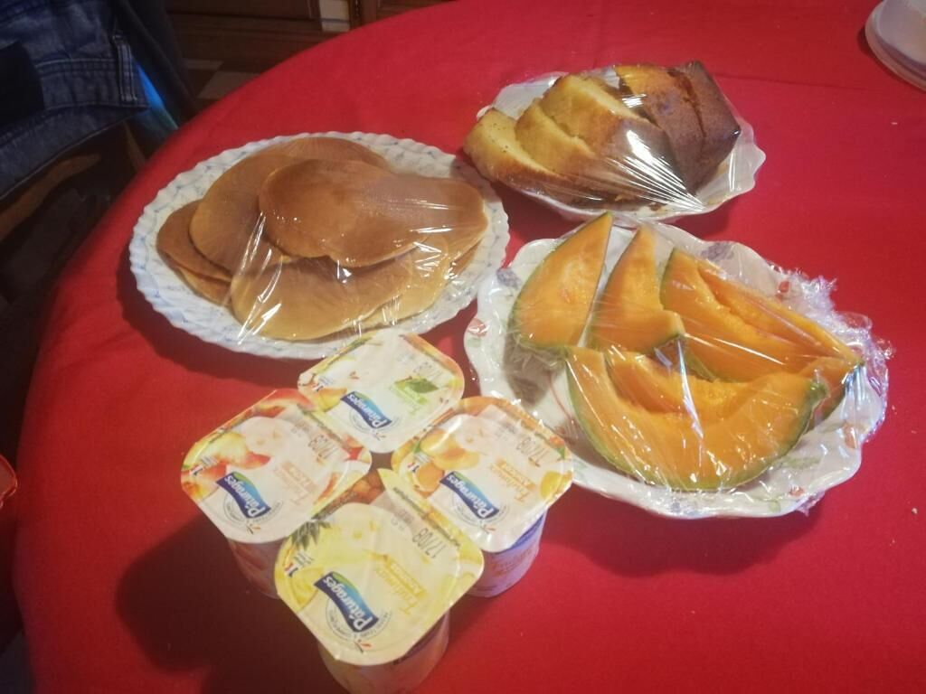 A table with food items including pancakes, a wrapped pastry, and yogurt cups.