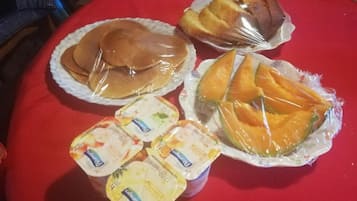A table with food items including pancakes, a wrapped pastry, and yogurt cups.