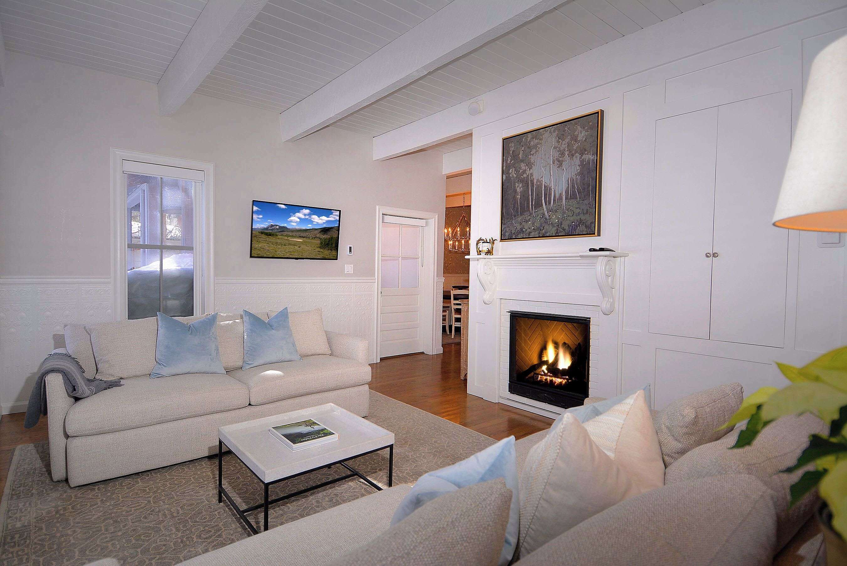 A living room with a fireplace, a sofa, a coffee table, and a television.