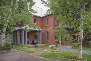 A two-story brick house with a covered porch and a small garden area.