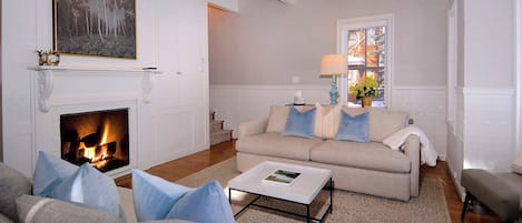 A living room with a fireplace, a sofa set, a coffee table, and a window with a view.