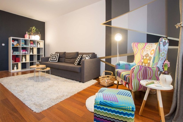 Living room with double sofa bed, armchair and shelf with books and decoration.