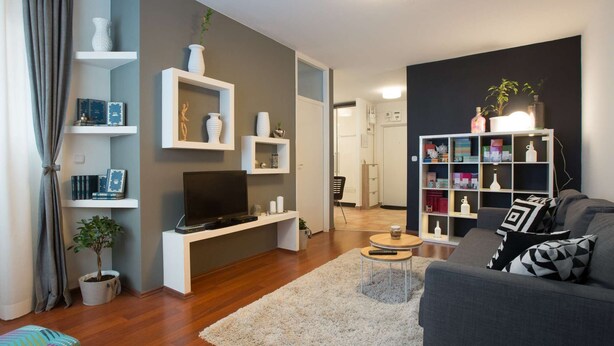A modern living room with a grey sofa, a TV on a white stand, a bookshelf, and a small coffee table. - One bedroom apartment with free parking, WIFI (Zagreb)