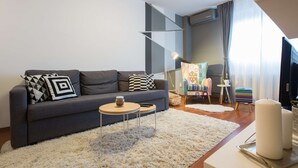 A modern living room with a grey sofa, a small round table, and a colorful chair. - One bedroom apartment with free parking, WIFI (Zagreb)