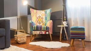 A cozy room with a colorful armchair, a small side table with a teapot, a wicker basket, and a fluffy rug. - One bedroom apartment with free parking, WIFI (Zagreb)