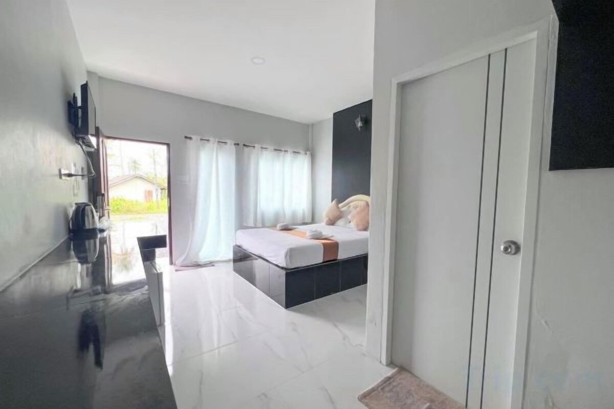 A modern bedroom with a bed, a bedside table, and a view of the outdoors.