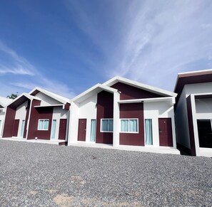 A row of modern, two-story buildings with a consistent architectural style, featuring large windows and doors, and a gravel driveway. - BM Beach Resort (La-ngu)