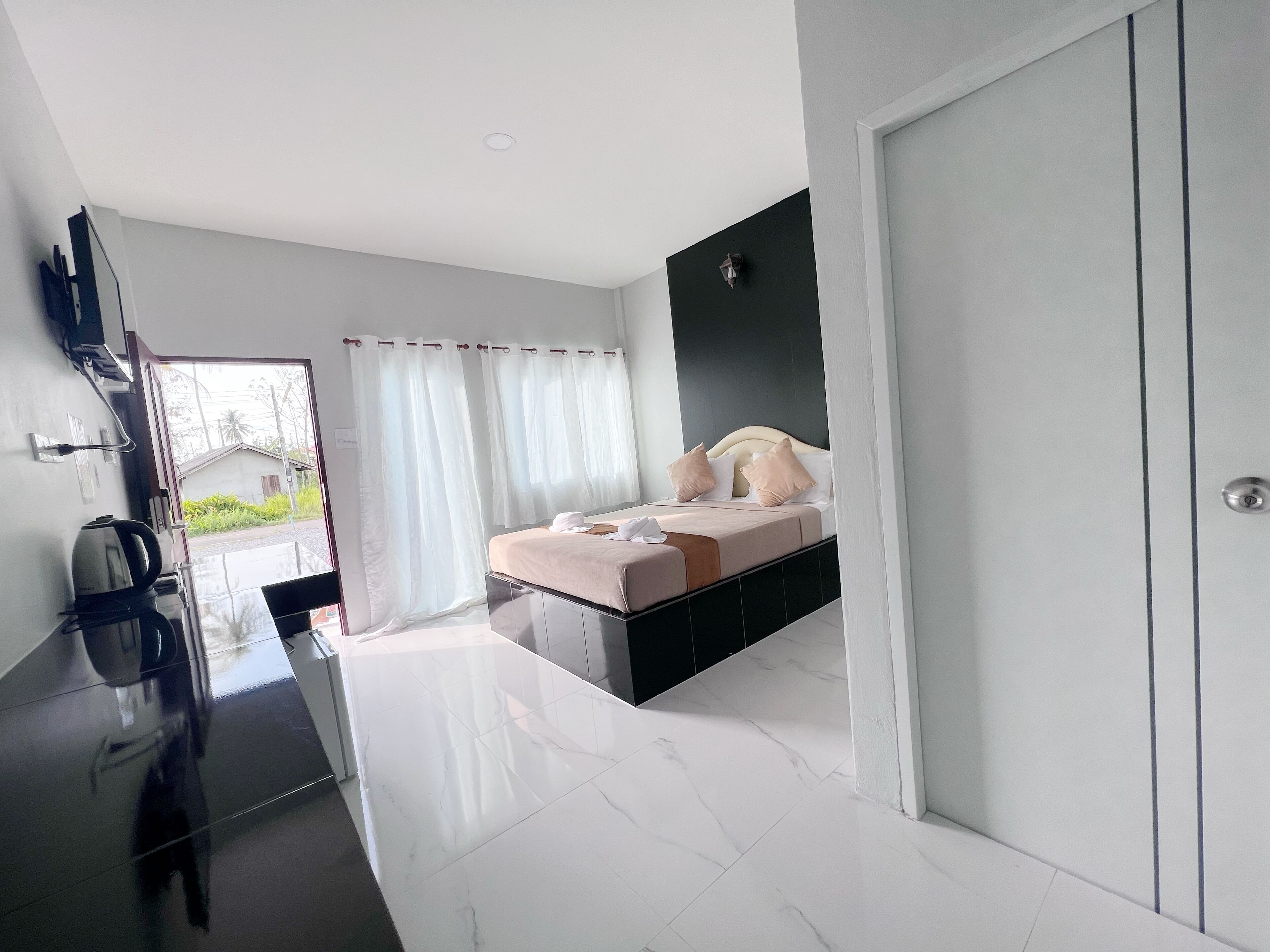 A modern bedroom with a bed, a TV, and a bathroom.