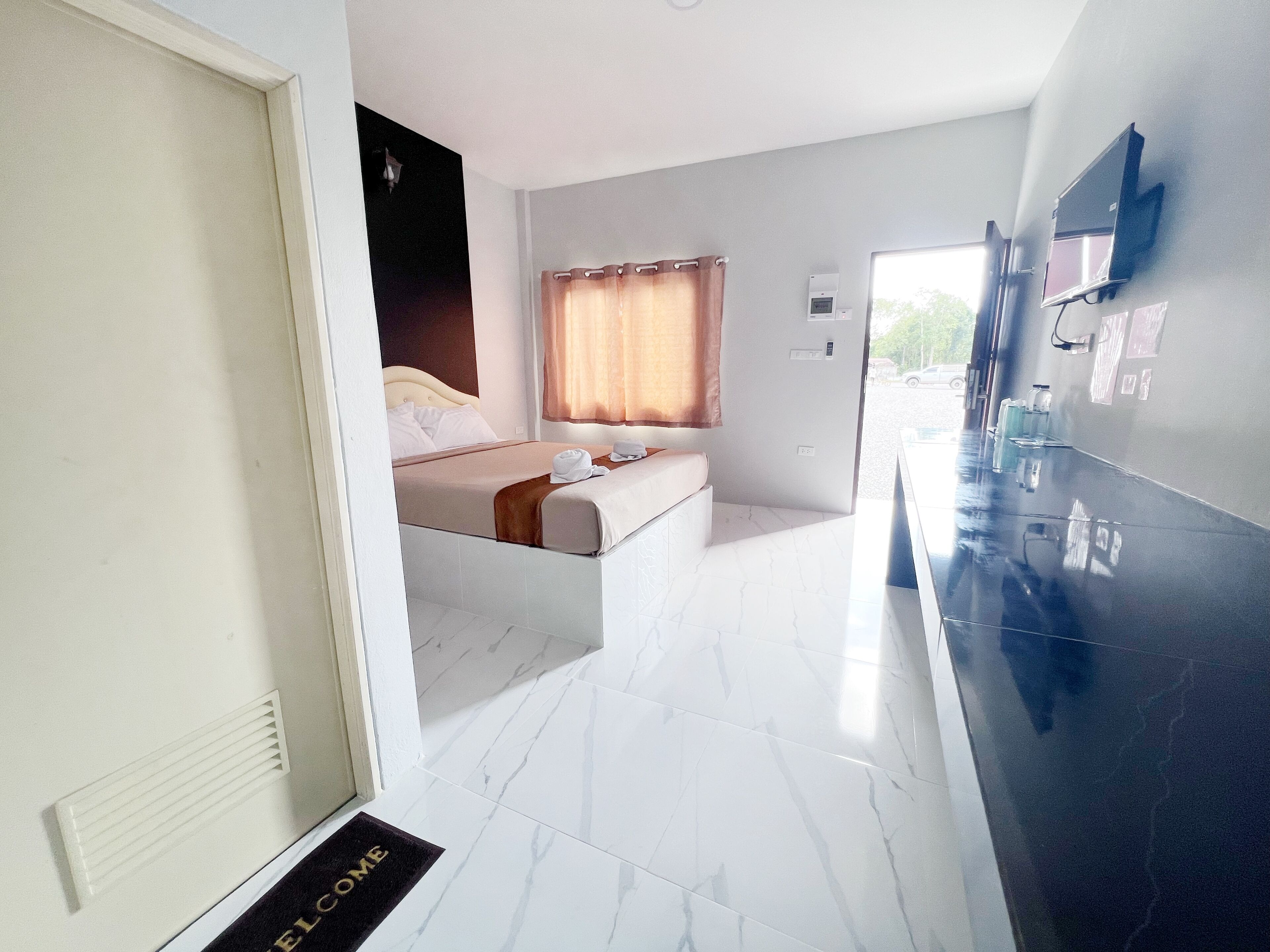 A modern hotel room with a bed, a bathroom, and a reception area.